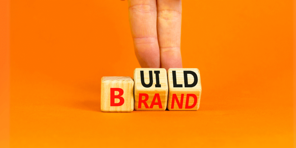 Why Every Business Needs Strong Branding Wooden blocks spelling Build Brand on orange background, symbolizing brand development strategy