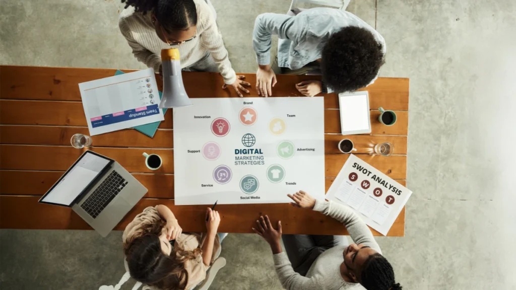 Team discussing digital marketing strategies and agency planning Overhead view of a marketing team analyzing digital strategies and SWOT analysis at a wooden table